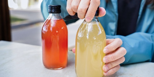 A person opening two bottles of their new juice beverages that have been created with the help of a beverage formulation expert. 