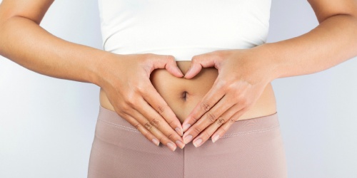A hand heart over a stomach representing digestive health 