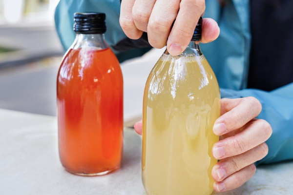 A person opening two bottles of their new juice beverages that have been created with the help of a beverage formulation expert. 