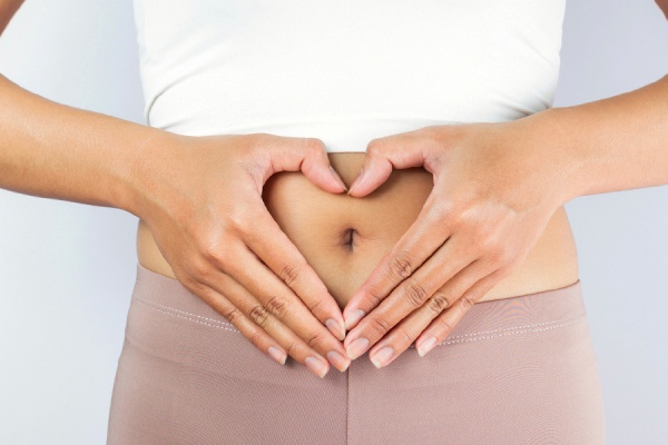 A hand heart over a stomach representing digestive health 